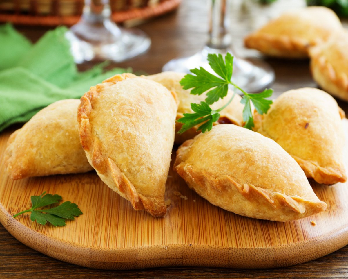Empanadas are made by folding dough over a stuffing, which may consist of m...